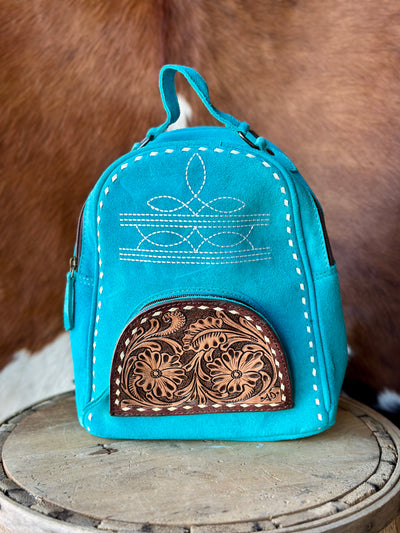 Western-Inspired Suede Backpack Enhanced by Hand-Tooled Leather pocket and trending boot stitch pattern.