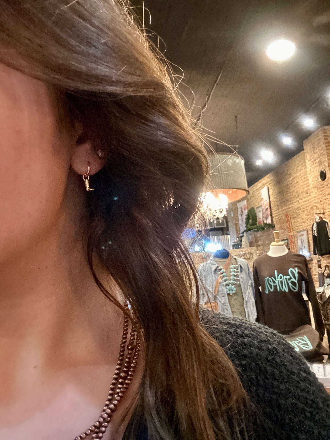 The Hailey Cowboy Boot Hoop Earrings modeled by a Broker Leather Employee.