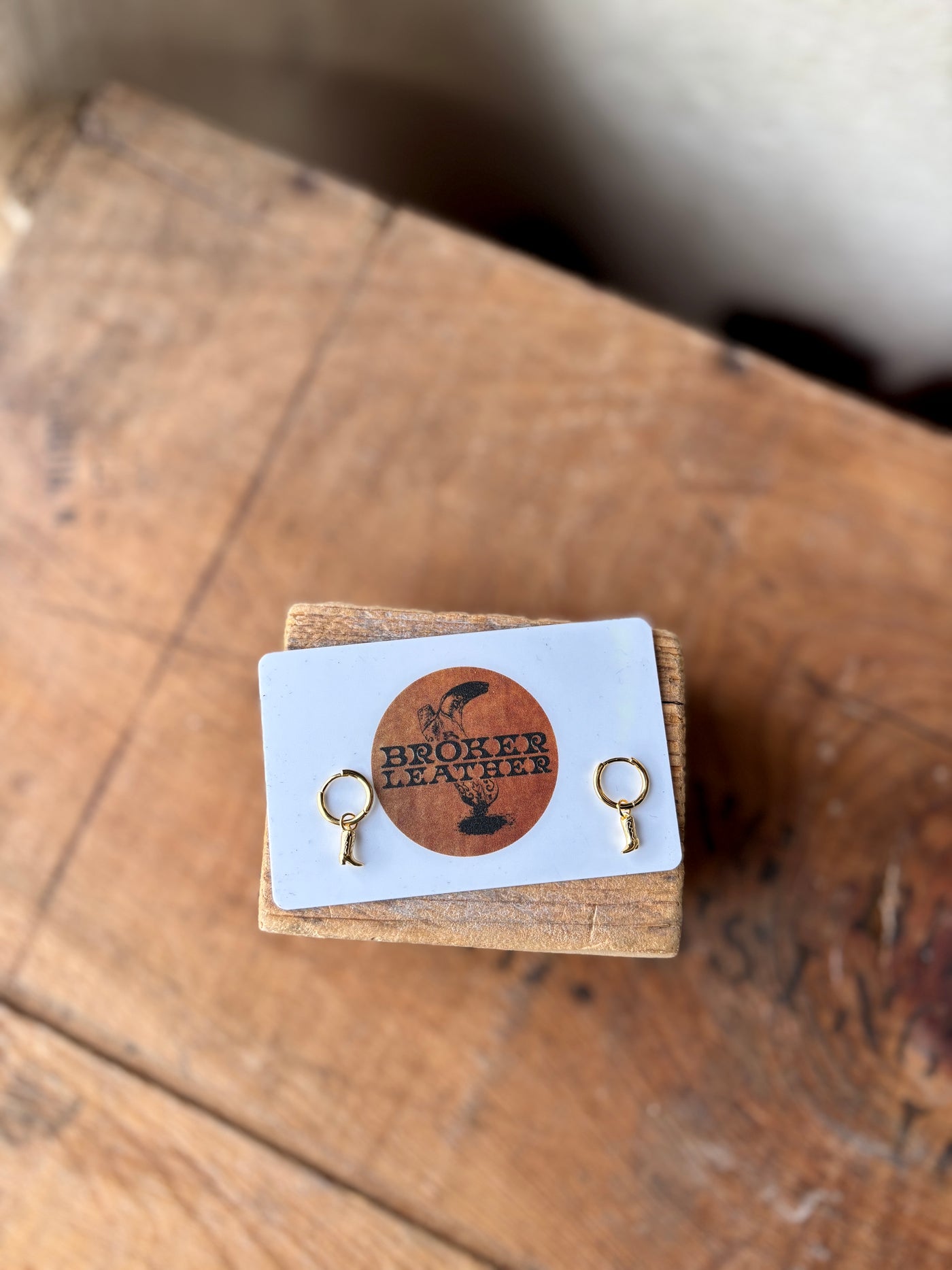 The Hailey Cowboy Boot Hoop Earrings photographed with a Broker Leather gift card for size comparison. 