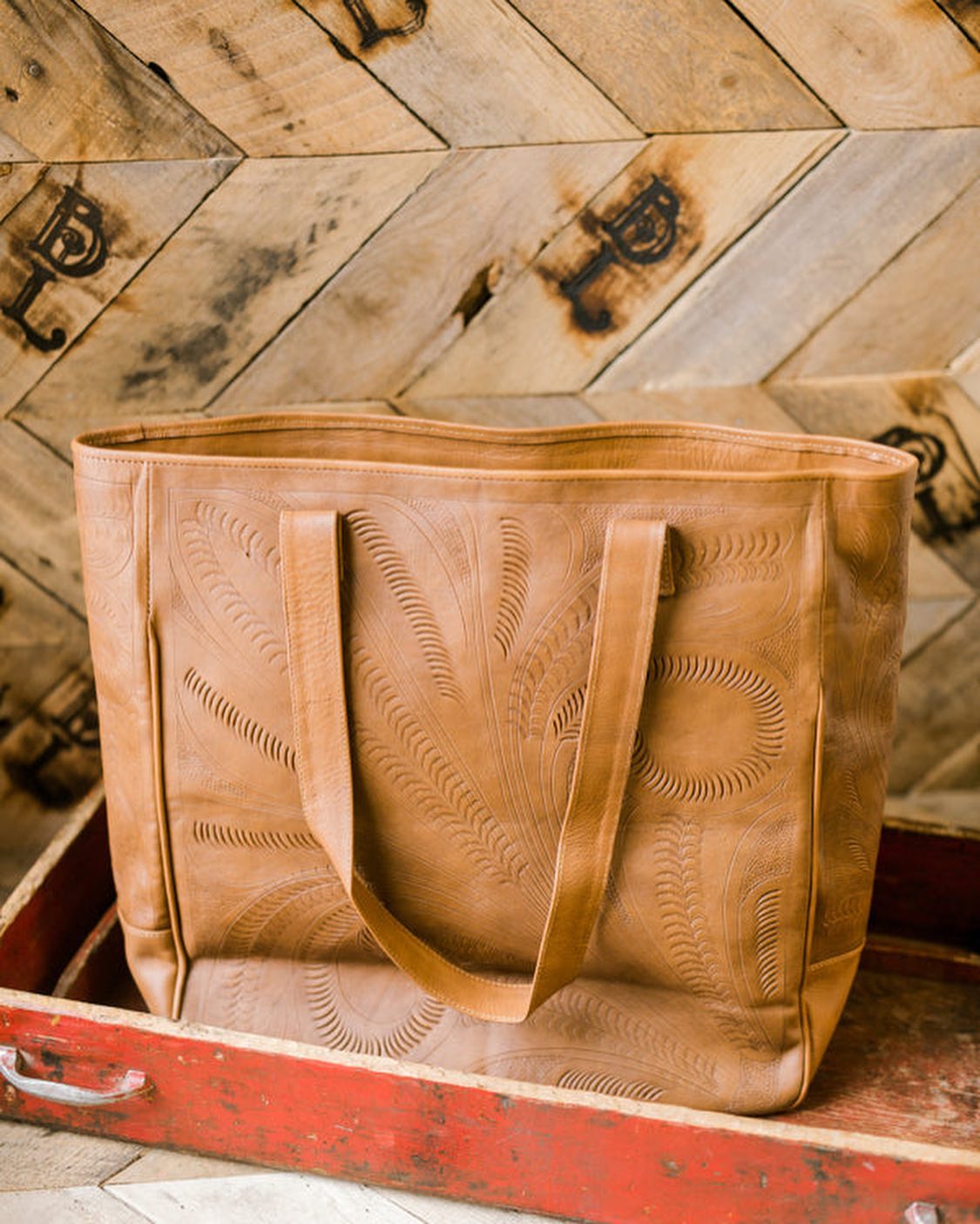 Spacious hand-tooled leather tote bag with multiple interior pockets.