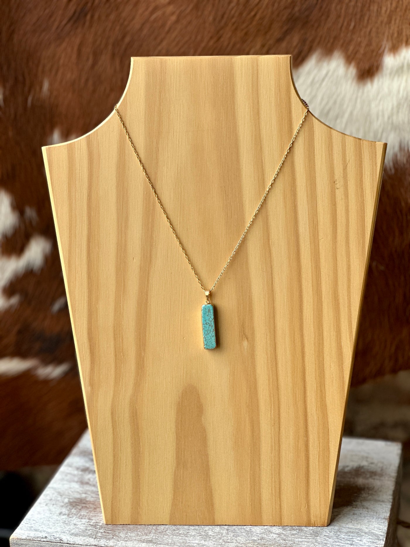 Detail shot of gold chain and turquoise bar pendant with intricate marbling / matrix.