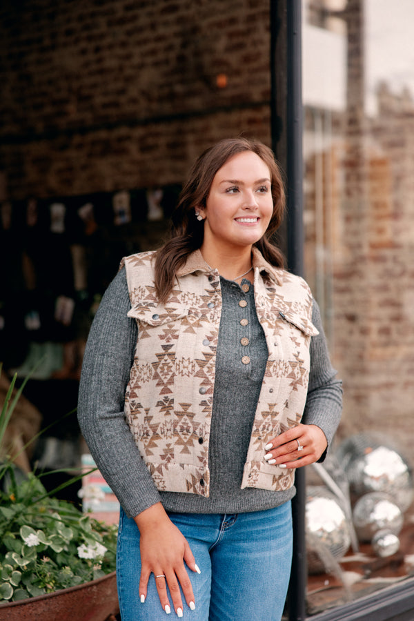 A Broker Leather employee modeling the new Hooey Binx Mommy-n-Me Vest which is neutral colors and features an Aztec pattern and shearling lining.