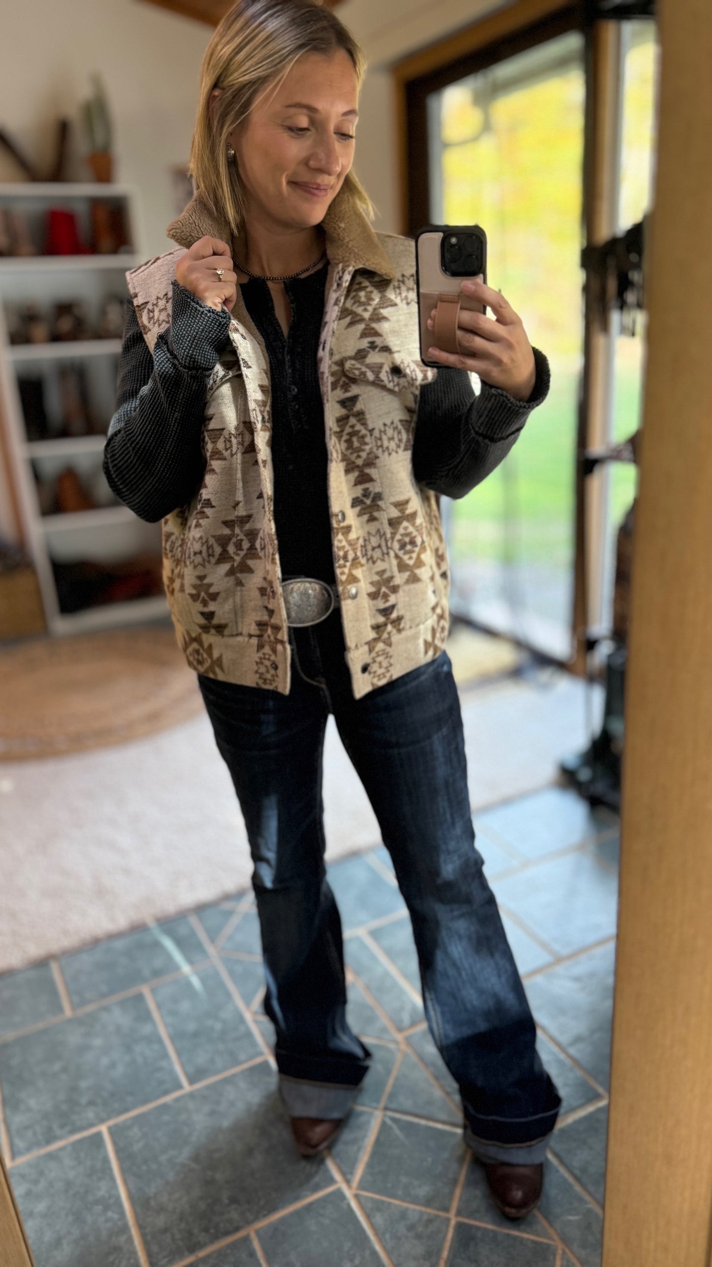 A Broker Leather employee modeling the Neutral Aztec Hooey Binx Mommy-n-Me Vest with Shearling Lining.