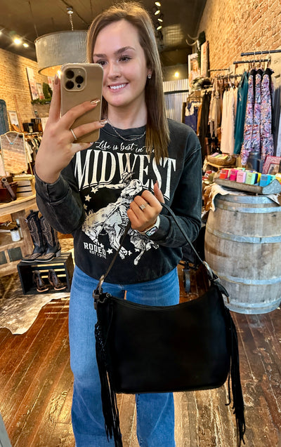 Gracelyn, a Broker Leather employee modeling the Jesse Fringe Hobo Buckled Bag [Black] to show size reference.