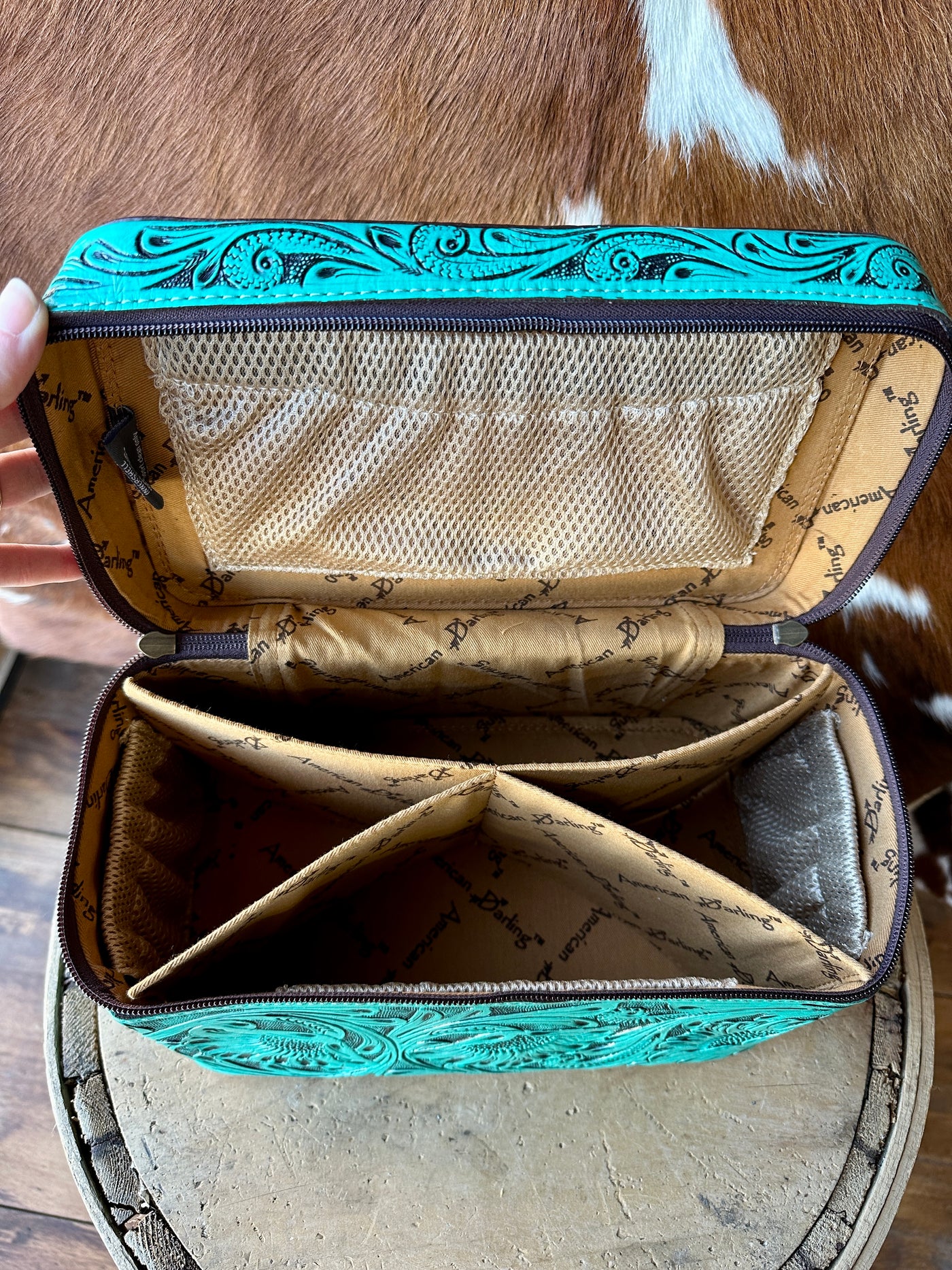 A western boutique genuine leather cosmetic case features intricate tooling, multiple pockets, and a removable divider, perfect for organizing your beauty essentials.