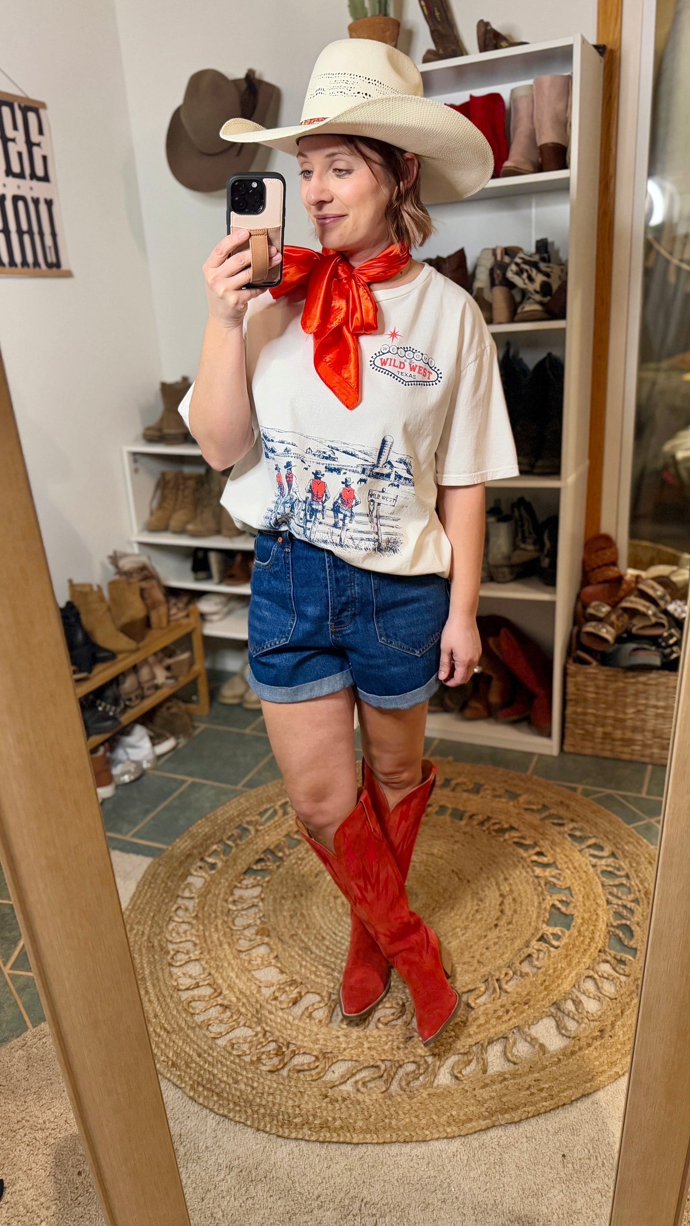 Model wearing Justine Wild West Tee styled with denim and bright red cowgirl boots.