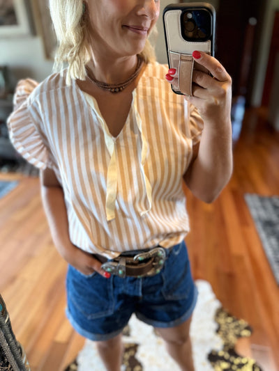 Woman taking a mirror selfie wearing a striped shirt with optional front bow with denim shorts and a western belt and copper Navajo Pearls.