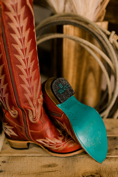 Close-up of Lane Lexington Boots showcasing their bold ruby red leather, easy on/off zipper, and signature turquoise soles.