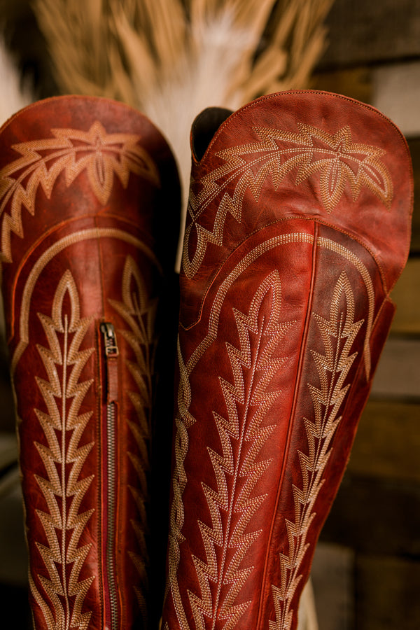 A close-up of Lane Lexington Boots showcasing the tall shafts adorned with incredible boot stitching in the bold ruby red leather.