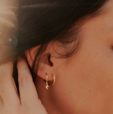 A model pushing her hair back to show the Latricia Lightning Bolt Hoop Earrings representing the thunder in her heart.