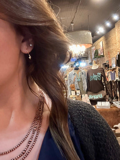 A Broker Leather employee modeling the Latricia Lightning Bolt Hoop Earrings paired with a copper Navajo Pearl Necklace.