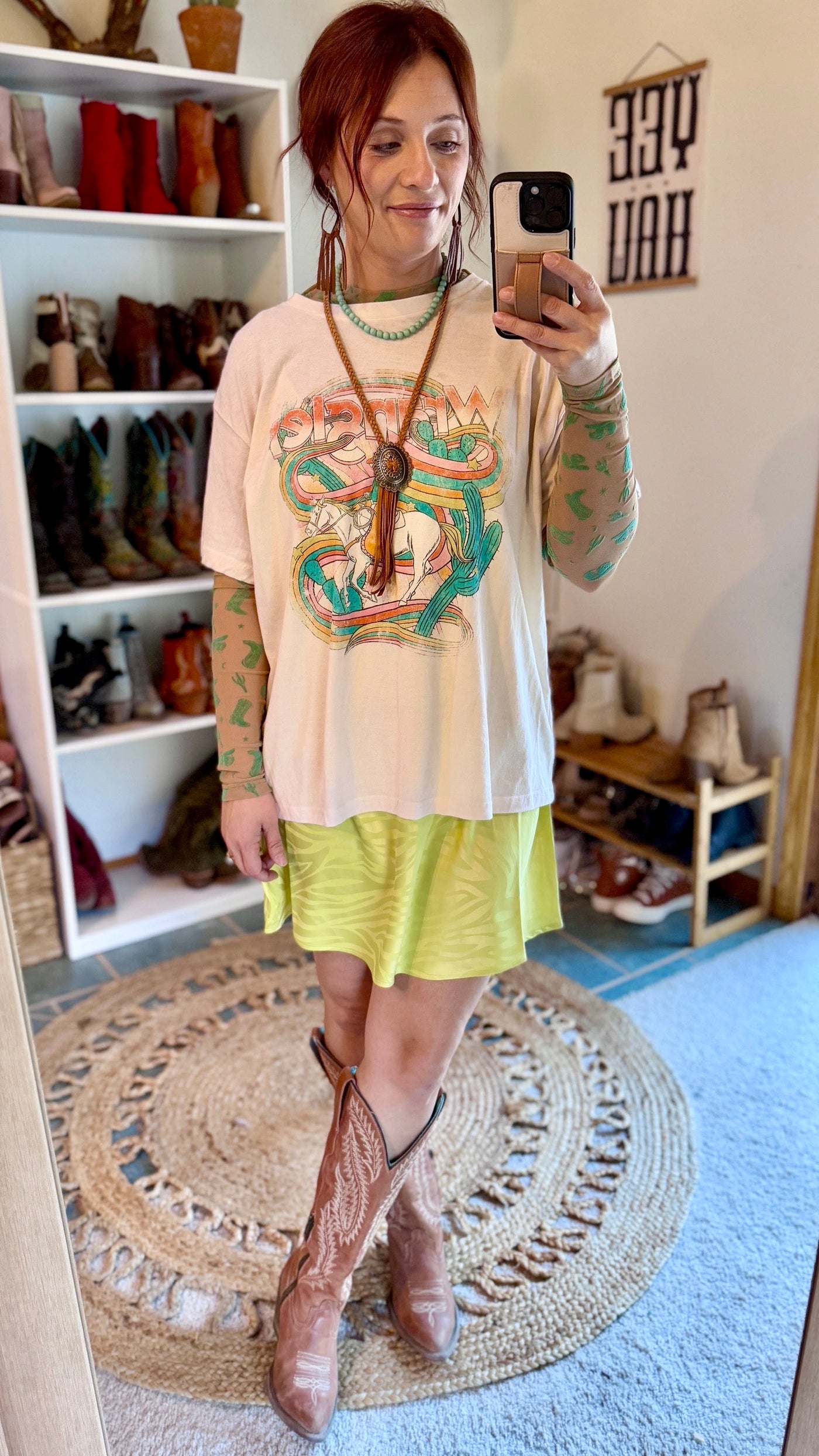 Western-themed mesh top in a nude/tan color featuring turquoise boots, hats, and cacti paired with a a neon green skirt and graphic tee for a trendy fashion statement.