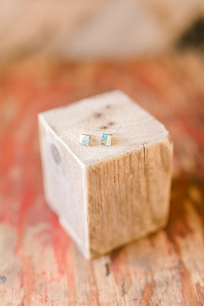 Tiny square turquoise stud earrings with natural stone variation and gold-framed edges