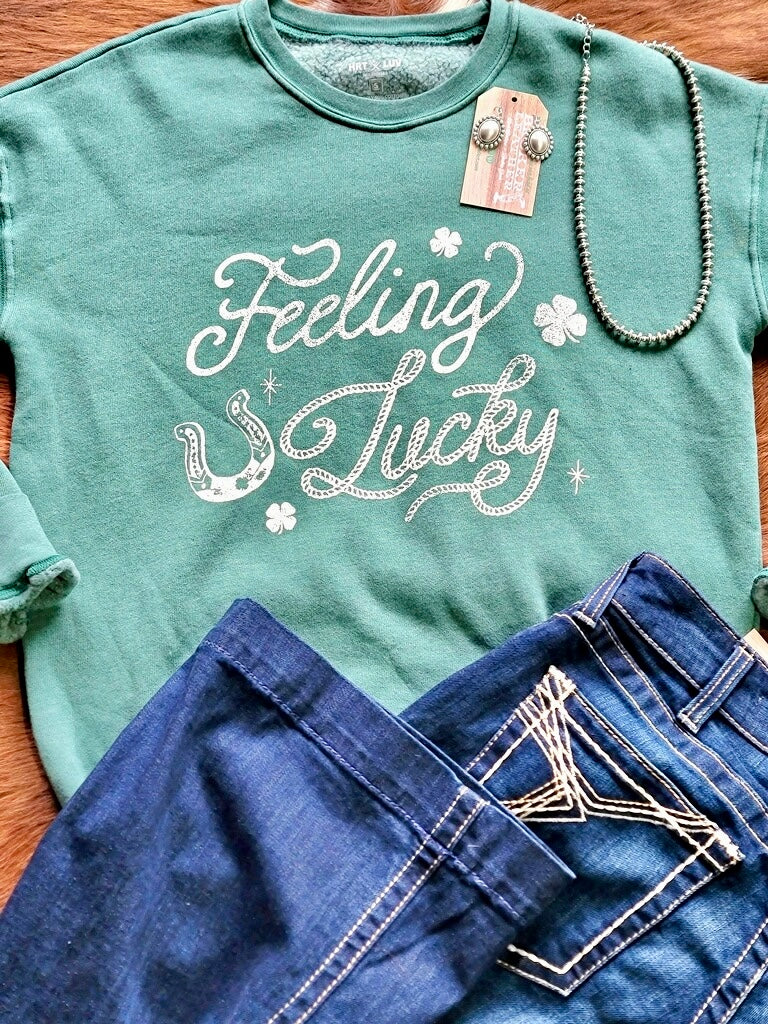 Broker Leather outfit inspiration flatlay featuring a St. Patrick's Day themed crewneck, Navajo Pearls, and Ariat Denim.