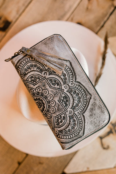 Western-style leather wristlet with intricate tooled floral pattern.