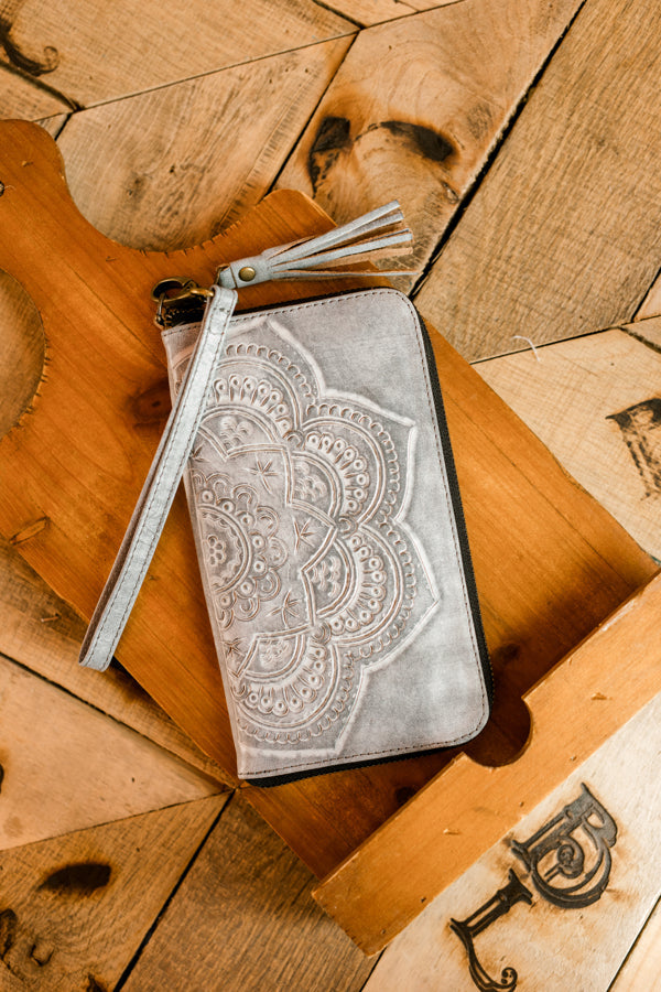 Bone-colored tooled leather wristlet with floral mandala design and wrist strap.