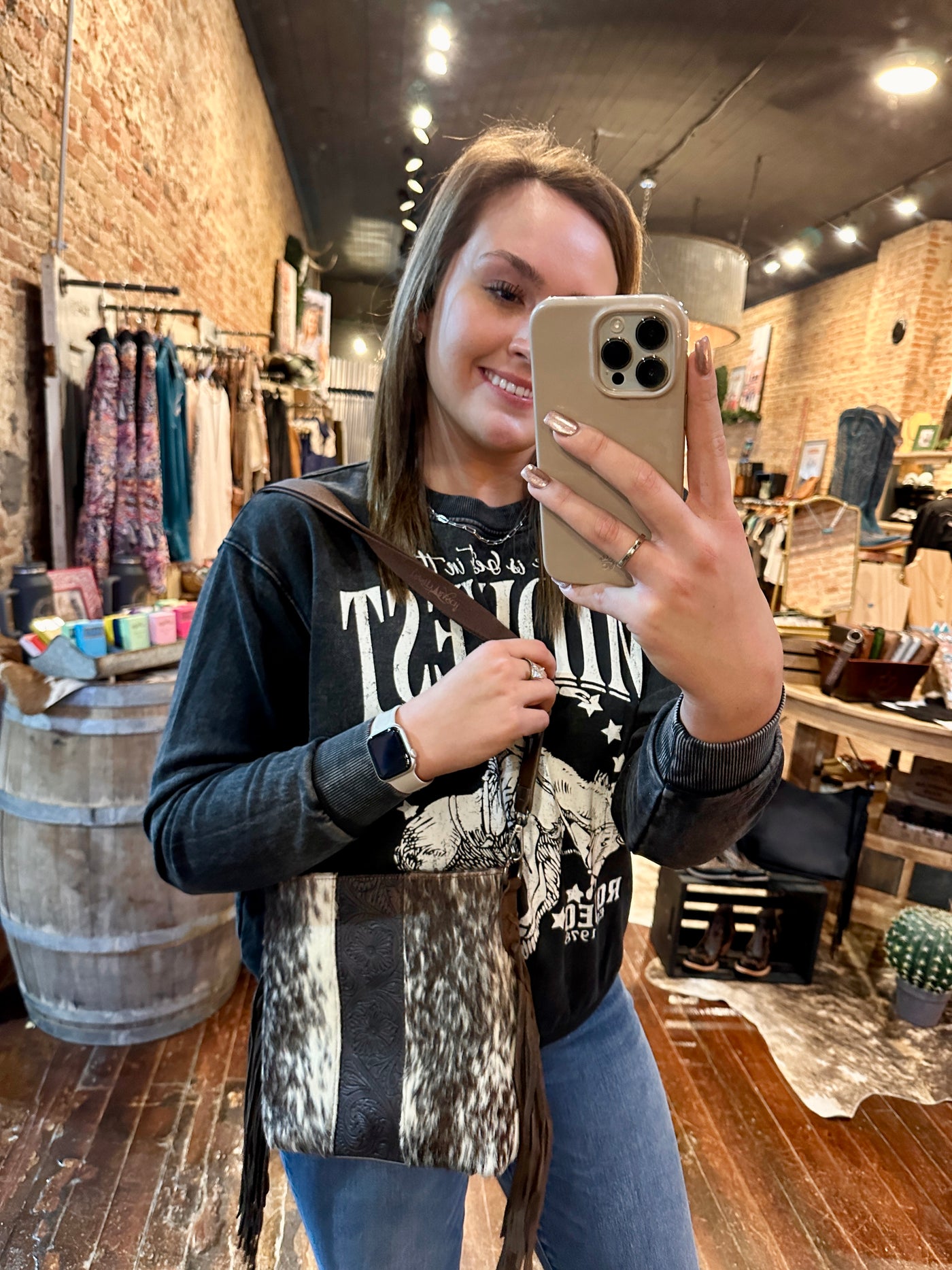 A Broker Leather employee modeling the McCoy Cowhide & Fringe Crossbody Bag for size reference.