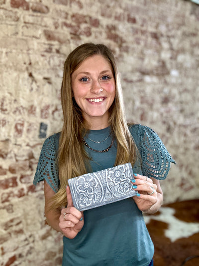 Hand-tooled bone leather McCrae Tooled Slim Checkbook Cover Wallet with zipper coin pouch held by Broker Leather employee for size reference.