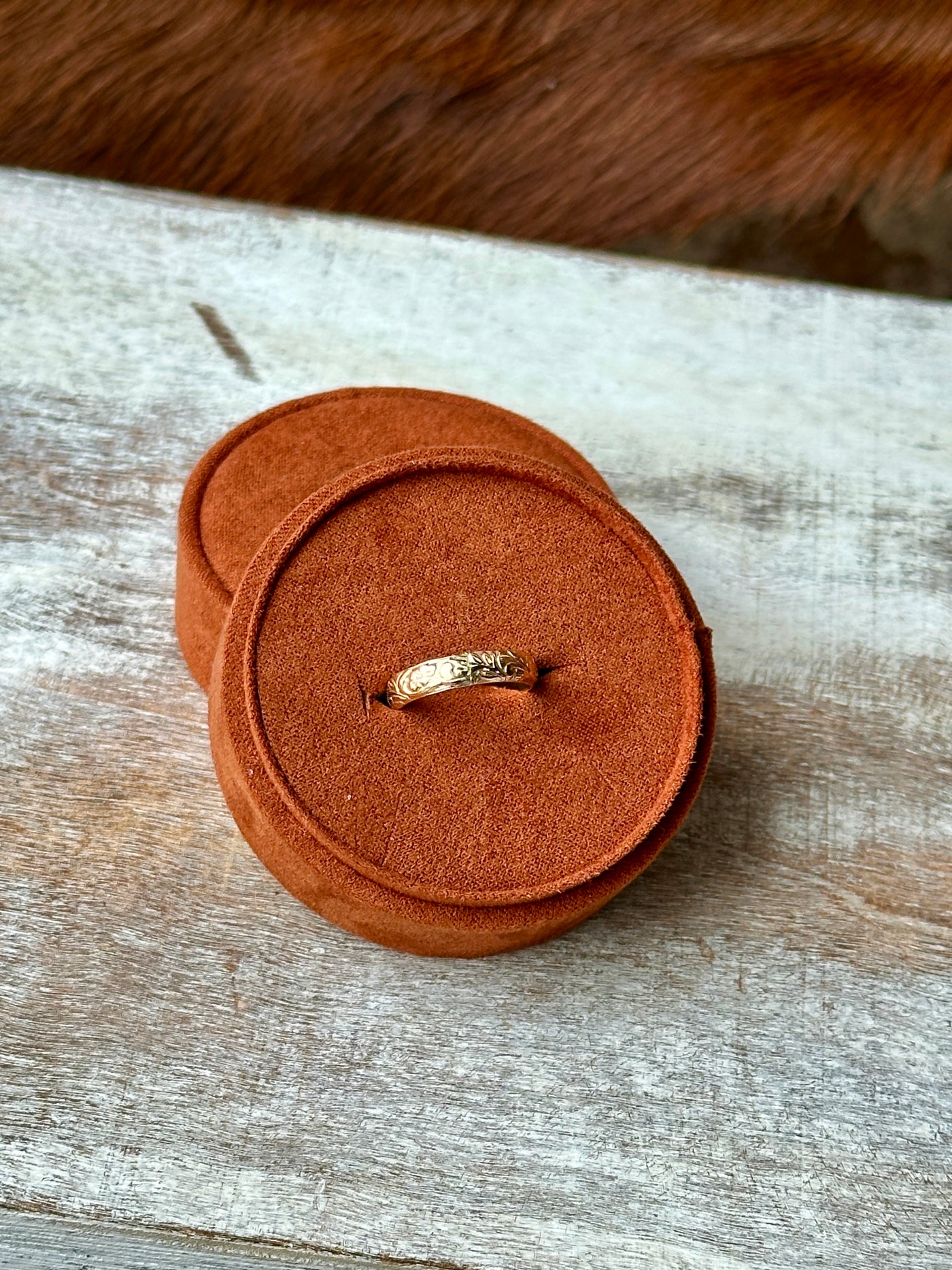 Gold stacker ring with Western floral engravings displayed in a felt ring box.