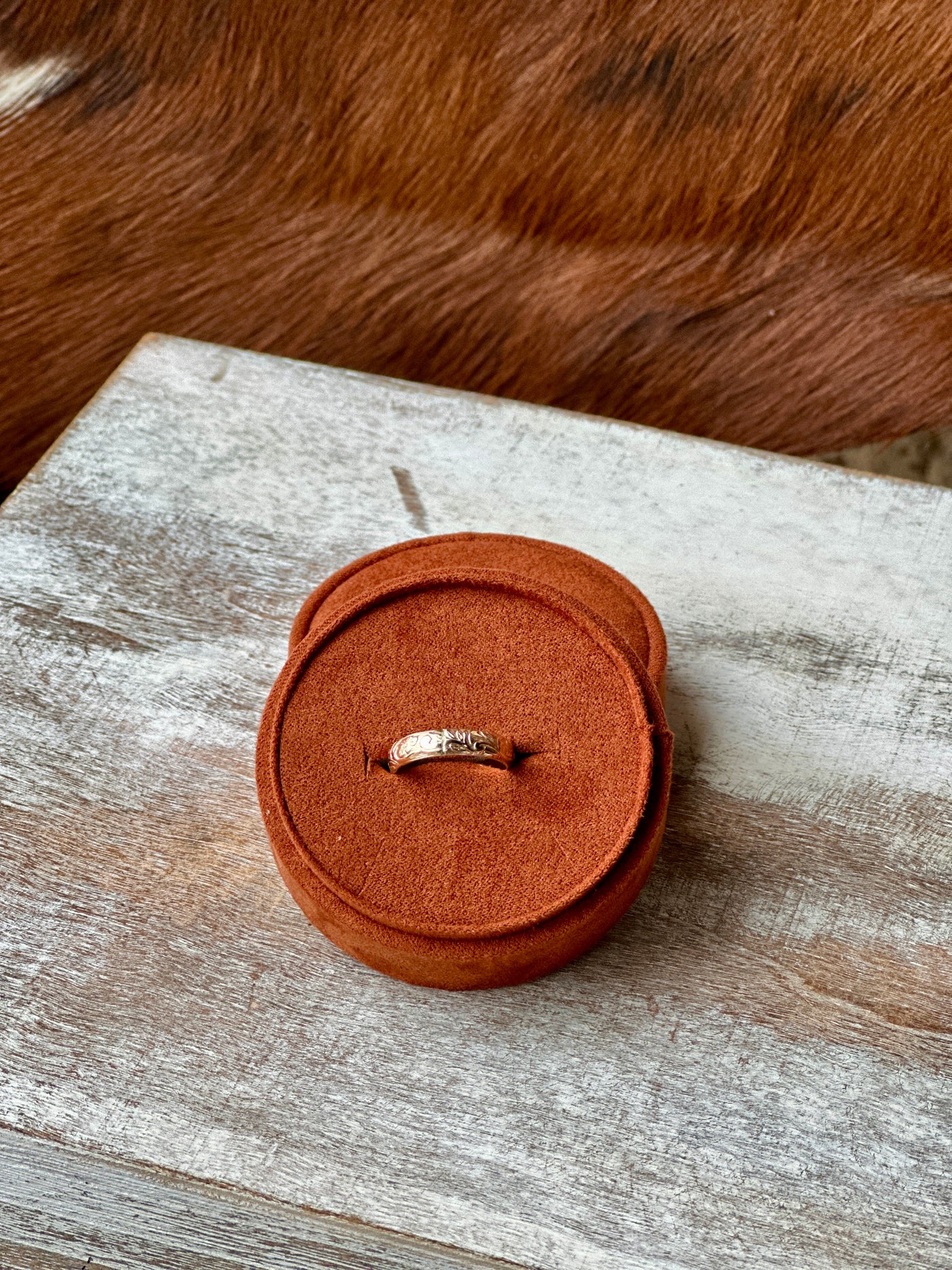 The Moana Floral Gold Stacker Ring showing intricate engraved details in a jewelry box for relative size comparison.