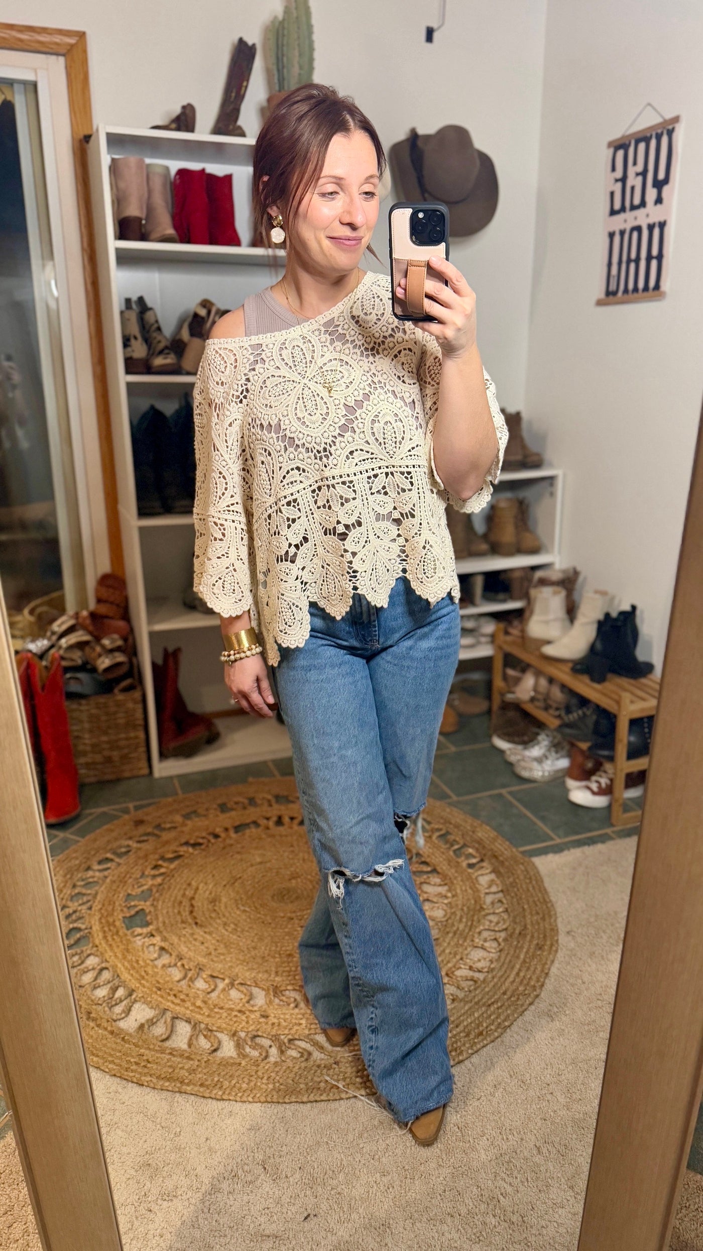 Boho-inspired white crochet lace top with wide bell sleeves paired with jeans and boots.