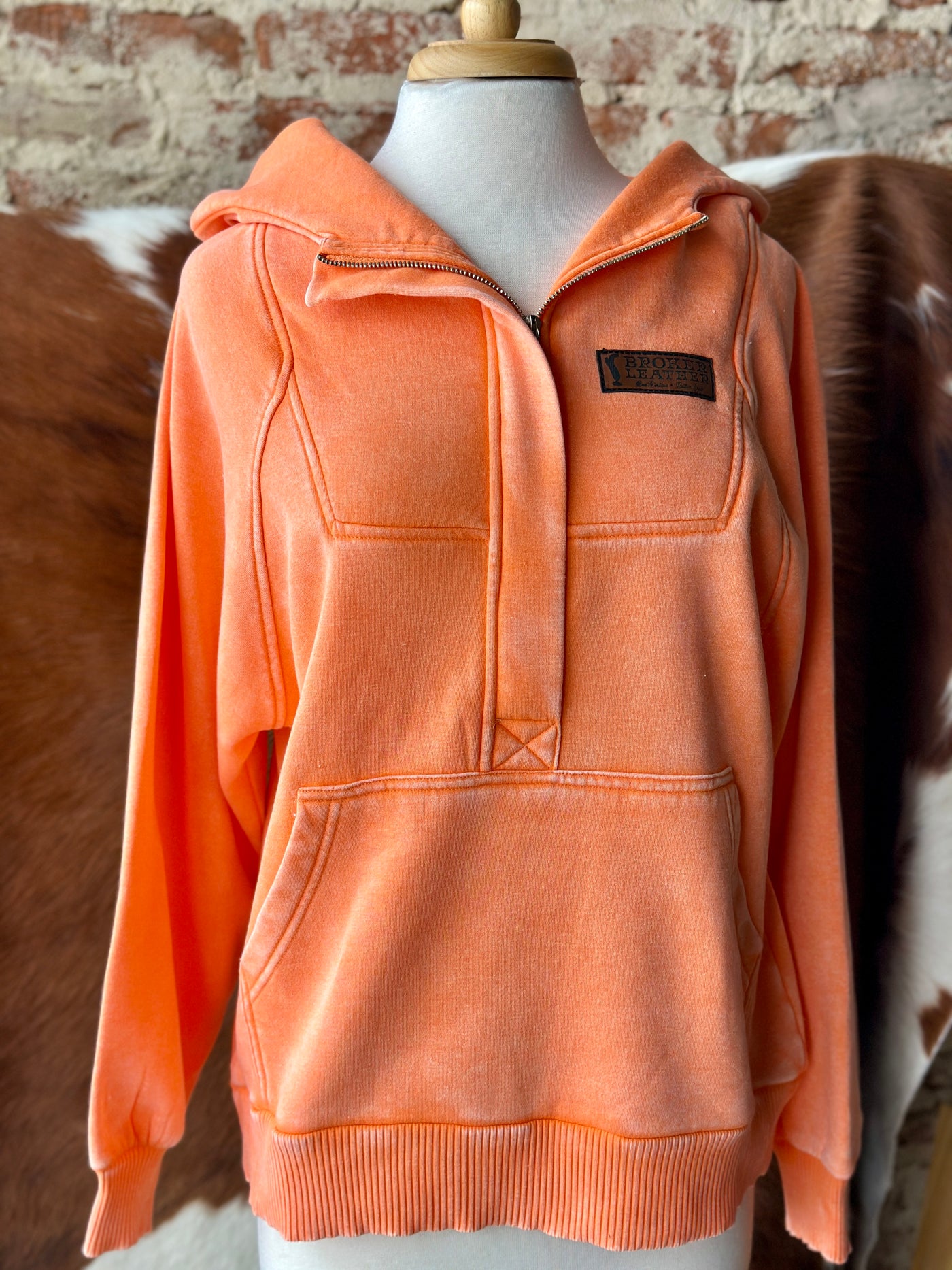 Close-up of No Sidelines Hoodie showcasing cotton-blend fabric, quarter-zip detail, and leather logo.