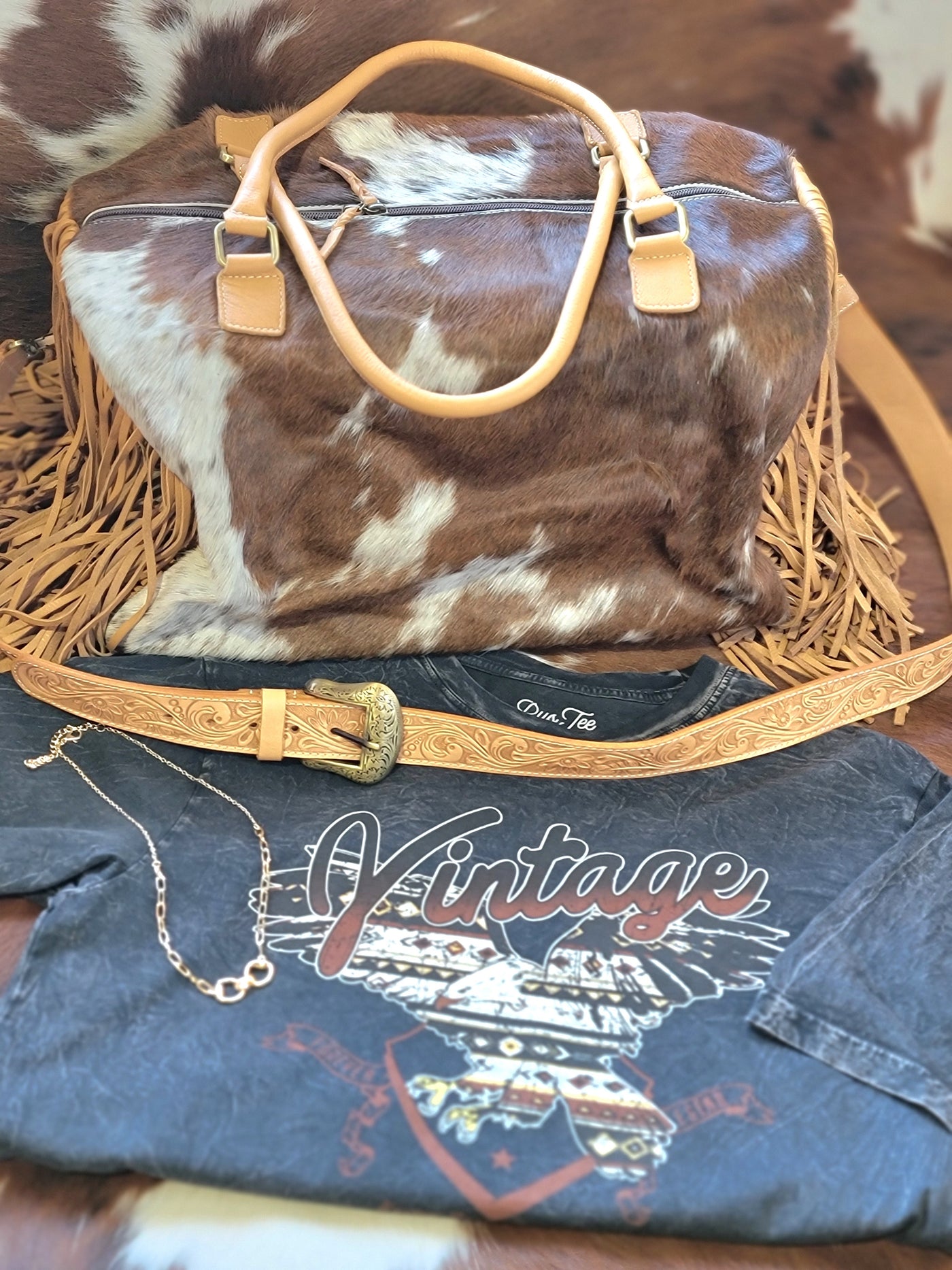 Pictured is a flat lay Octavia Fringe Weekender Duffel Bag in genuine hair-on-hide cowhide and leather.