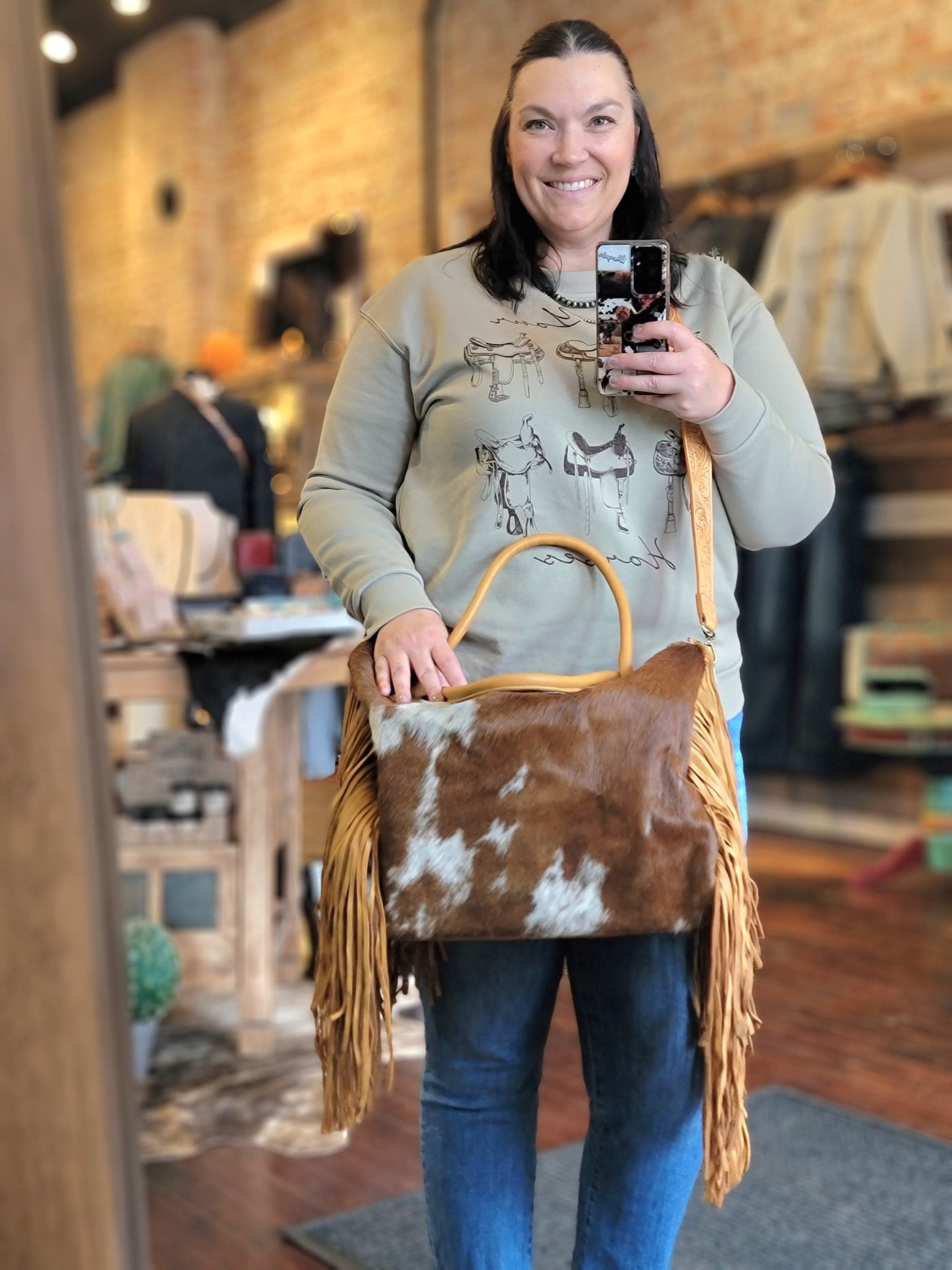 Model at Broker Leather showing a close-up of genuine cowhide texture on the Octavia Fringe Weekender Bag.