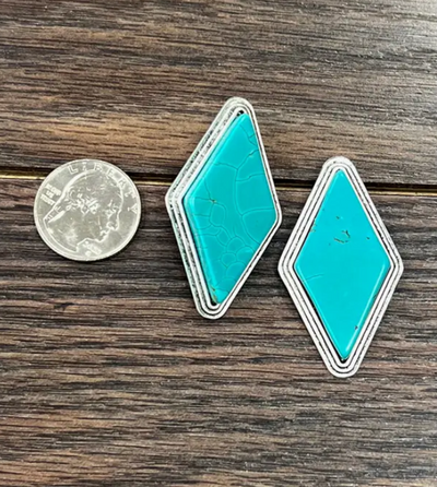 Stock photo of our Reed Turquoise Diamond Post Earrings next to a quarter to show size reference.