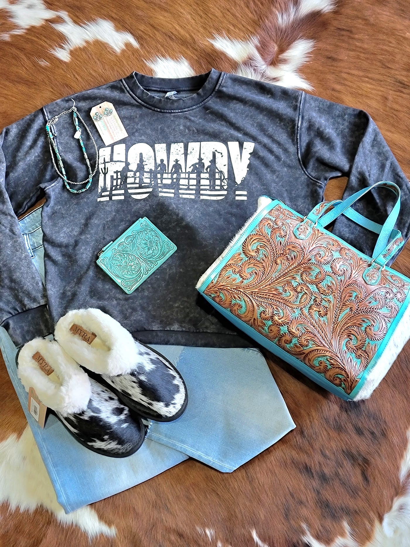 Ryggen Genuine Cowhide Slippers show styled with a Howdy Crewneck sweatshirt, a tooled leather purse, and Navajo Pearls.