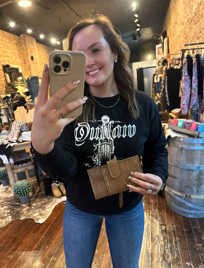 A Broker Leather employee modeling the Ricardo Floral Tooled Organized Wallet [Natural] to show the size of the wallet measuring Approx. 7.75" x 4.25".