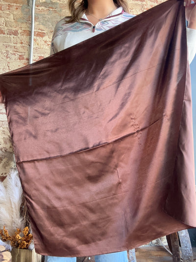 A person holding up the solid Roscoe Coffee Brown Wild Rag with a soft, silk-like texture, perfect for cowboys and cowgirls.