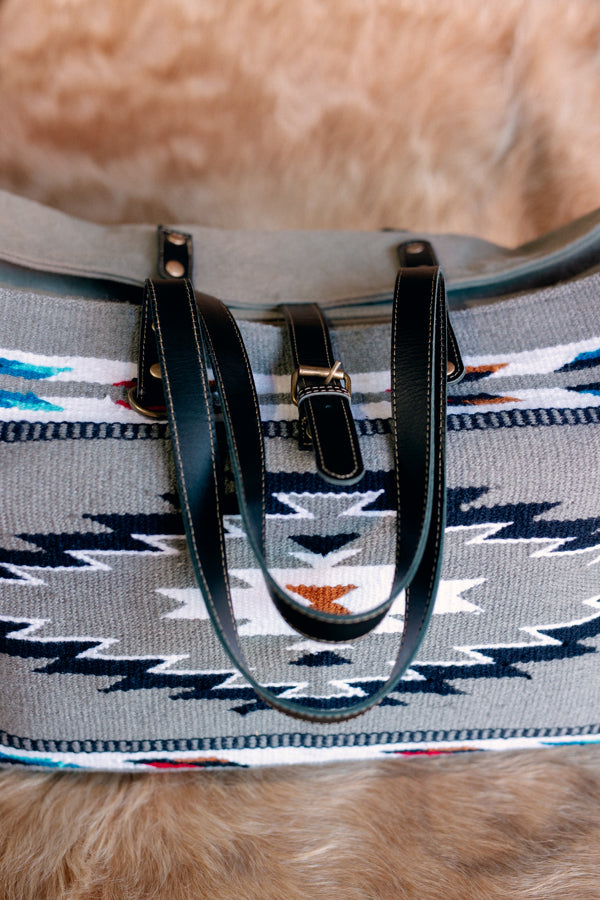 Close-up of Shelbie Saddle Blanket Weekender Bag showcasing its grey base color with red, white, blue, black, and gold accents.