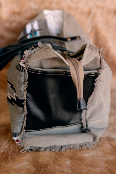 Flat lay of Shelbie Saddle Blanket Weekender Bag displaying its woven texture and sturdy 11-inch handle drop.