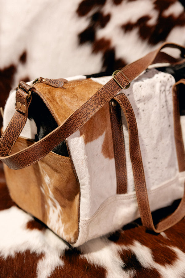 Genuine cowhide and leather weekender bag featuring textured leather handles.