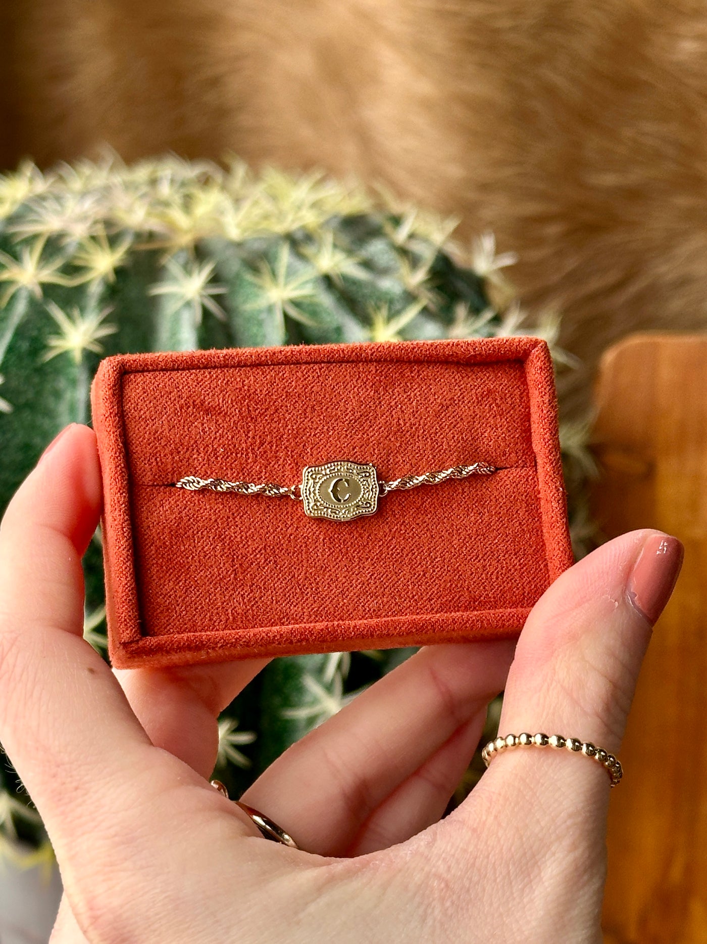 Close-up of gold belt buckle initial charm – dainty Western bracelet design
