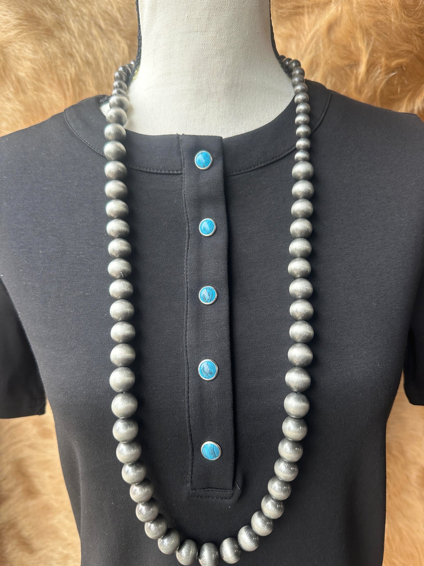 Close-up of turquoise pearl snap buttons on black Western-style Tilly shirt