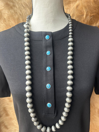 Close-up of turquoise pearl snap buttons on black Western-style Tilly shirt