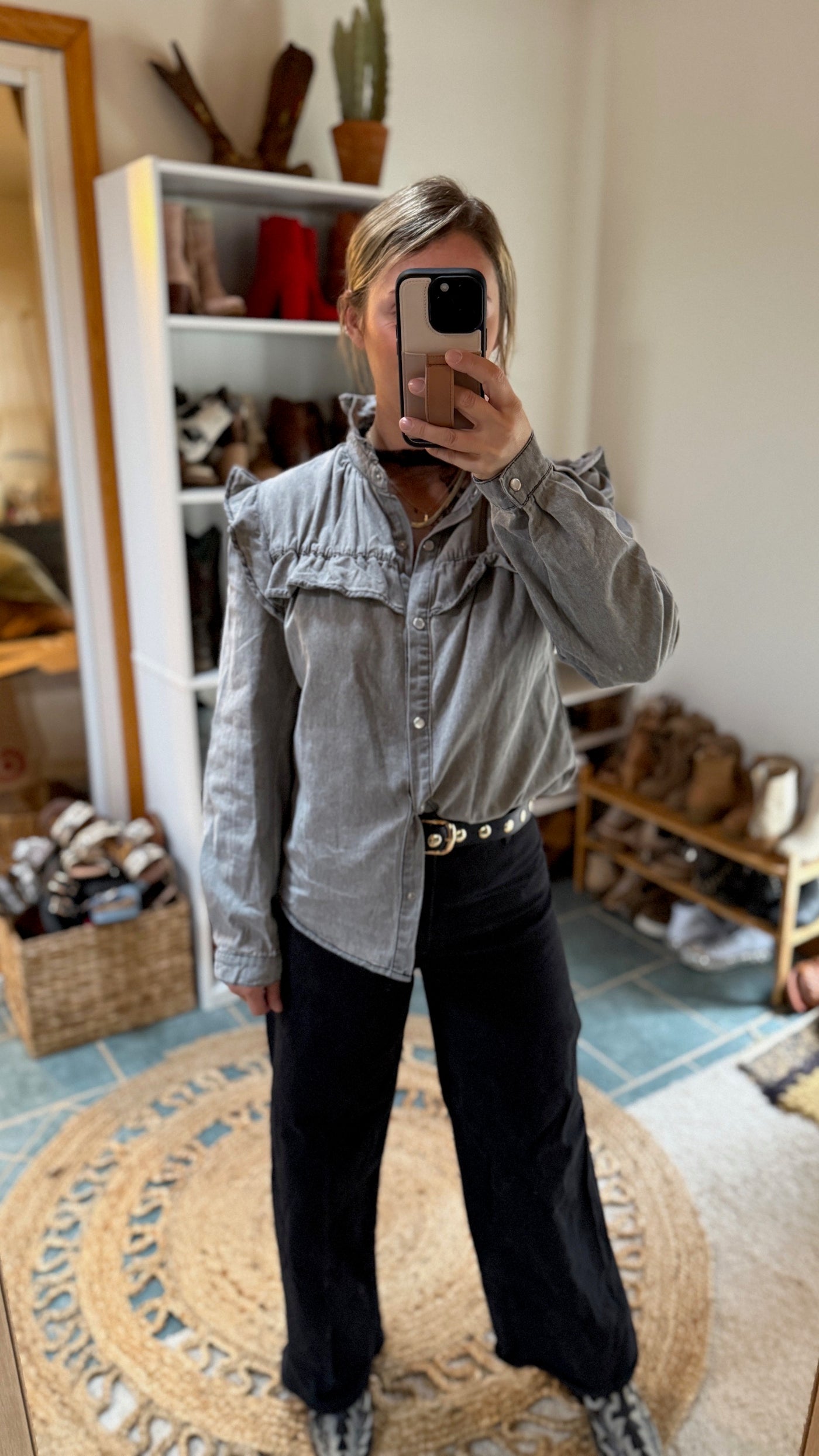 Western inspired look from model at Broker Leather of Voyager Ruffled Denim Shirt in light grey hand-dyed denim, featuring elegant ruffled details and pearl snap buttons.