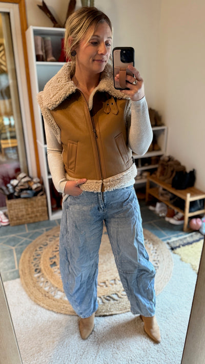 A Broker Leather employee modeling the Neutral shearling lined faux-leather Wallen vest that makes any outfit Western this winter.