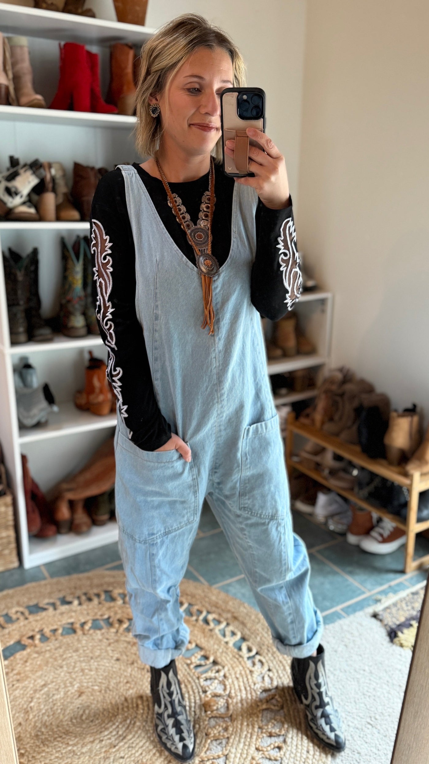 Woman modeling our Walton Black Boot Stitch Long Sleeve Top underneath a denim jumpsuit.