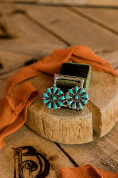 A pair of authentic turquoise earrings displayed in a traditional ring jewelry box for size comparison.