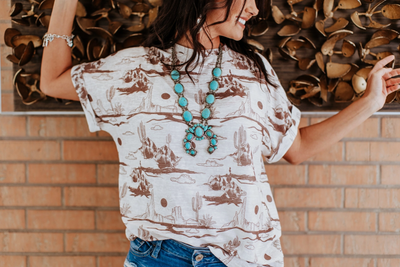 Wren Desert Scene Top modeled with a breezy fit, celebrating heritage and Western style.