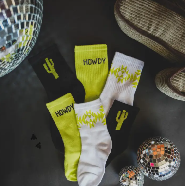 This set includes three pairs—one black pair with a neon green cactus on the ankle, one white pair featuring a neon green Aztec pattern on the ankle, and one neon green pair with a bold "Howdy" slogan on the ankle. 