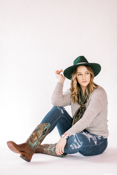 Cowgirl modeling our Mezzetta Solid Olive Green Wild Rag with jeans, boots, and a hat.