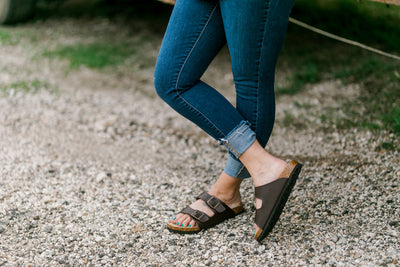 Close-up of adjustable buckle closures on dark brown sandals for customized fit